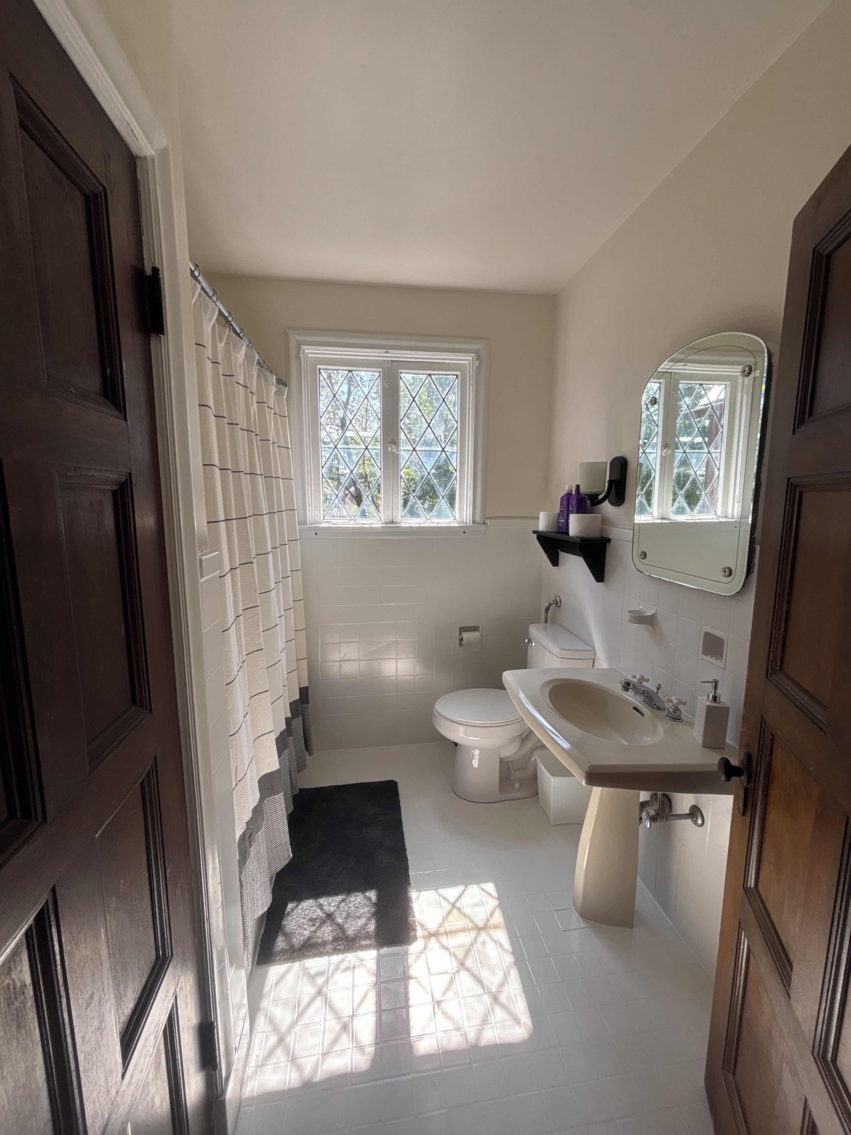 A bathroom with a toilet, sink, and window.