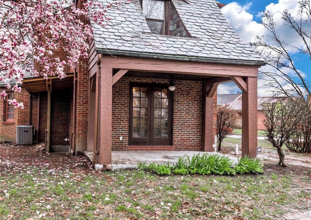 A brick building with a pitched roof and a covered porch.