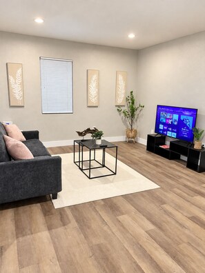 Ein modernes Wohnzimmer mit einem grauen Sofa, einem Couchtisch, einem Fernseher und Wanddekoration.