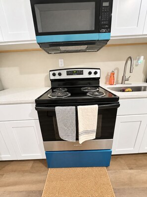 A kitchen with a black stove, a microwave above it, and a sink with a faucet. - Spacious 3BR Jacksonville Home—Sleeps Up to 8 (Jacksonville)