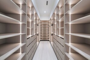 En modern och väl upplyst klädkammare med flera hyllor och lådor, präglad av en stilren och minimalistisk design.