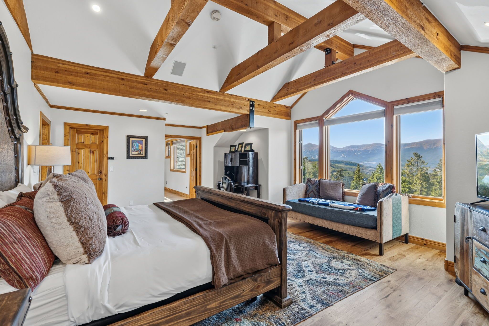 A bedroom with a large bed, a sofa, and a view of the outdoors.