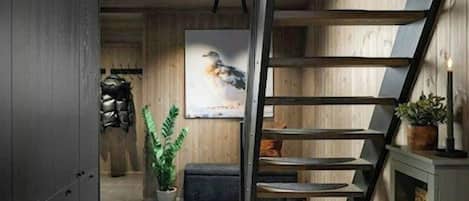 A modern interior with a wooden staircase, a kitchen area, and a living space.