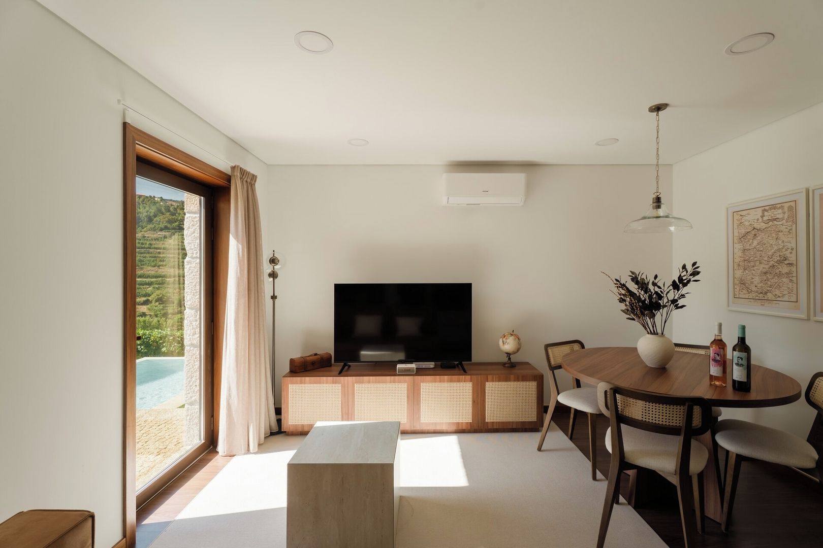 En moderne stue med et fladskærms-tv, møbler i træ og et spiseområde med et rundt bord og stole.