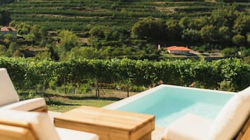 A poolside area with lounge chairs and a view of a vineyard.