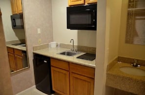 A compact kitchen with a dishwasher, a microwave, a sink, and wooden cabinets.