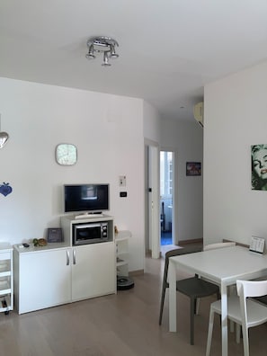 Un salon moderne doté d’un téléviseur à écran plat, d’un four à micro-ondes et d’un coin repas avec une table et des chaises.