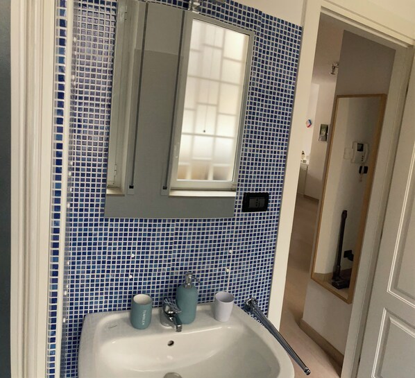 Une salle de bain avec un lavabo, un miroir et des carreaux de mosaïque bleus.
