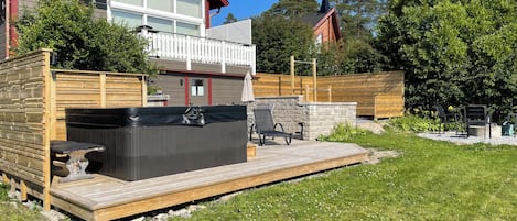 A residential property with a deck, hot tub, and outdoor seating area.