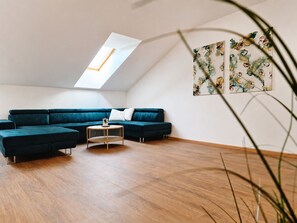 A modern living room with a sectional sofa, a round coffee table, and a skylight. - Loft Park Olomouc - Spacious 109 m² Loft with AC in City Centre (Olomouc)