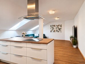 Et moderne køkken med en central ø, indbyggede skabe og et ovenlys.