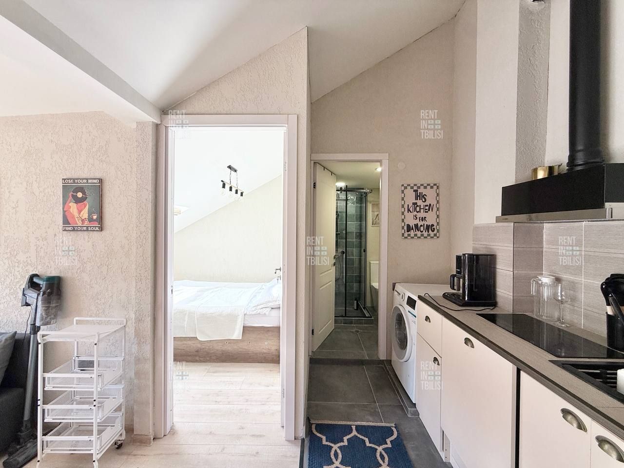 A compact hotel room with a kitchenette, a bed, a bathroom, and a view of the outside.