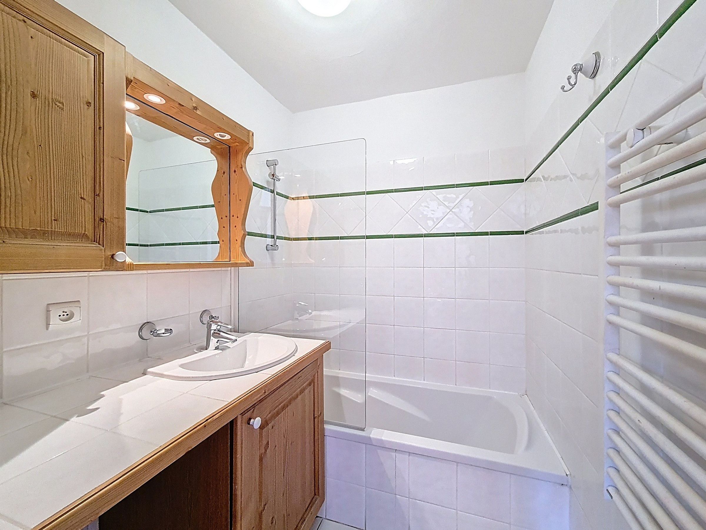 Une salle de bain avec un meuble-lavabo en bois, un miroir, un évier, une baignoire et une douche.