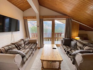 A cozy living room with two sofas, a wooden coffee table, and a TV mounted on the wall. - Apartment in Méribel, mountain view - 5 guests (Méribel)
