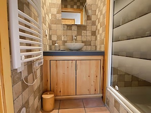 Un baño con un mueble de madera, un lavamanos blanco y un salpicadero de azulejos.