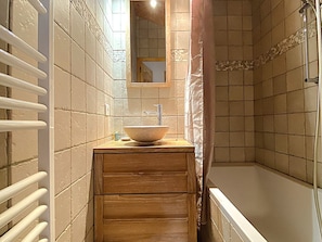A bathroom with a wooden vanity, a large vessel sink, a shower area, and a white towel rack. - Apartment in Méribel, mountain view - 5 guests (Méribel)