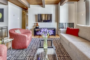 Una sala de estar con un sofá, un sillón y una mesa de centro de vidrio.