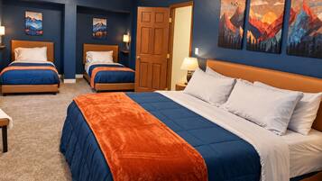 Een hotelkamer met een groot bed, twee kleinere bedden en een deur naar een andere kamer.