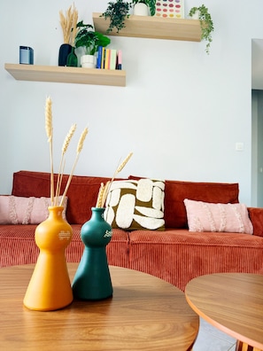 A living room with a red sofa, two vases with wheat stalks, and a wooden coffee table. - New Listing (Vouvray)