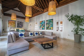 A spacious living area with a sectional sofa, a coffee table, and artwork on the walls. - 15 Bedroom Villa in the Old City (Cartagena de Indias)