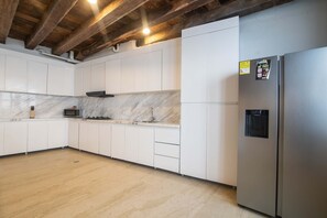 Een moderne keuken met witte kasten, een marmeren spatwand en een roestvrijstalen koelkast.