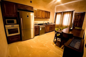 Cocina compacta con electrodomésticos integrados, zona de comedor y ventana con cortinas.