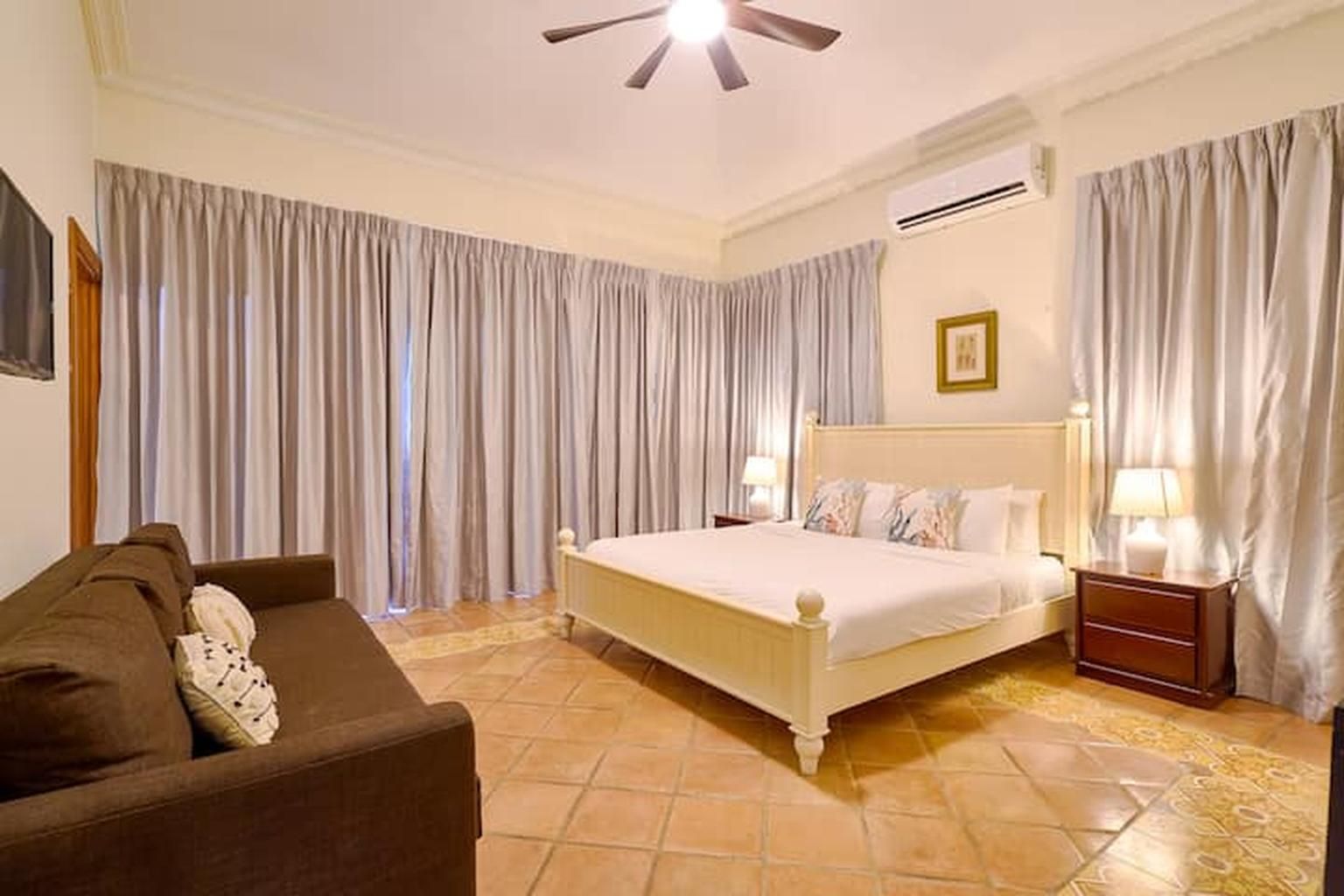 A bedroom with a bed, a nightstand, a lamp, and a ceiling fan.