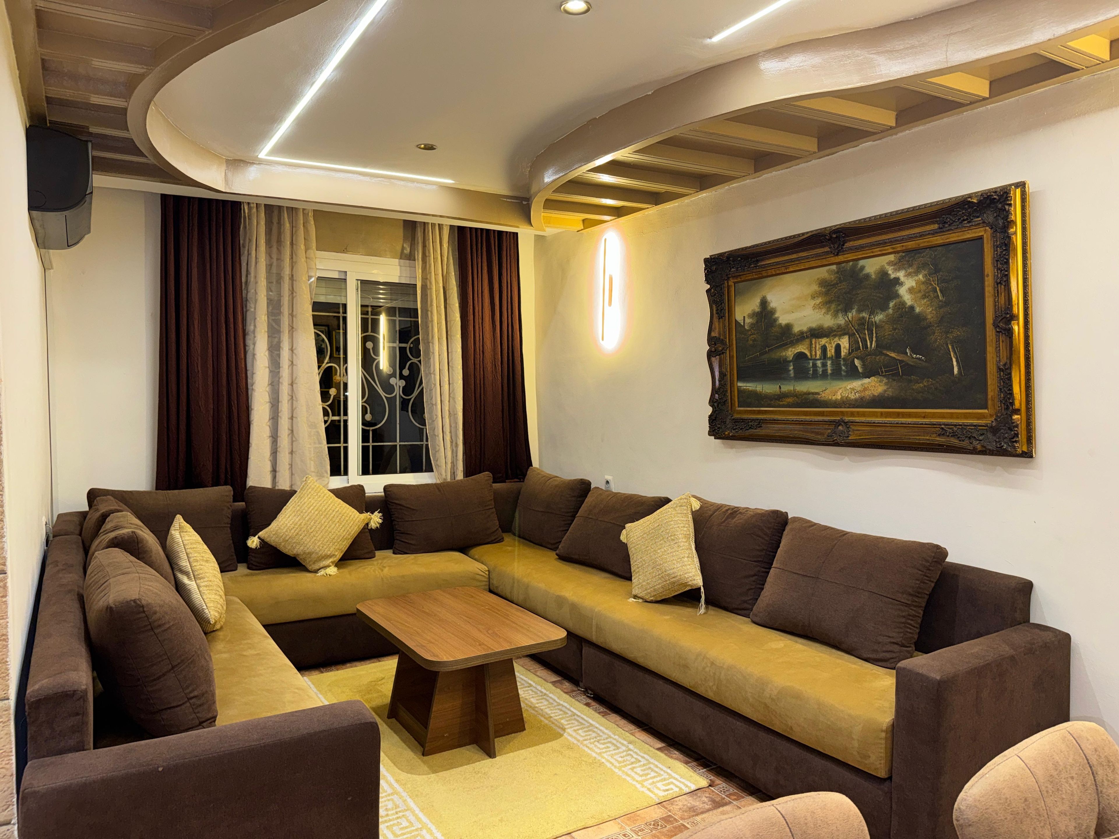 A living room with a sectional sofa, a coffee table, and a painting on the wall.