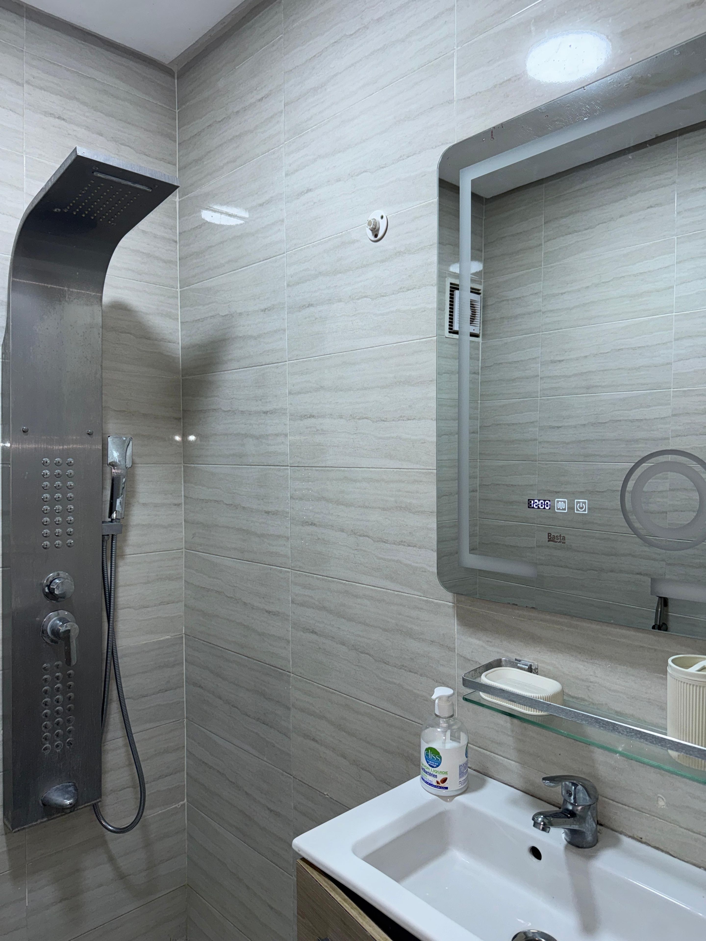 A modern bathroom with a shower, a sink, and a mirror.