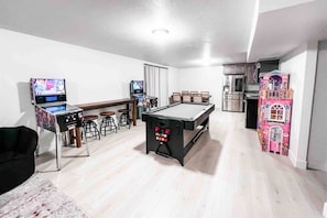 Un tavolo da biliardo in una stanza con un'area bar e una casetta dei giochi per bambini.