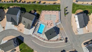 Una vista aerea di una zona residenziale con una piscina, diverse case e una strada curva.