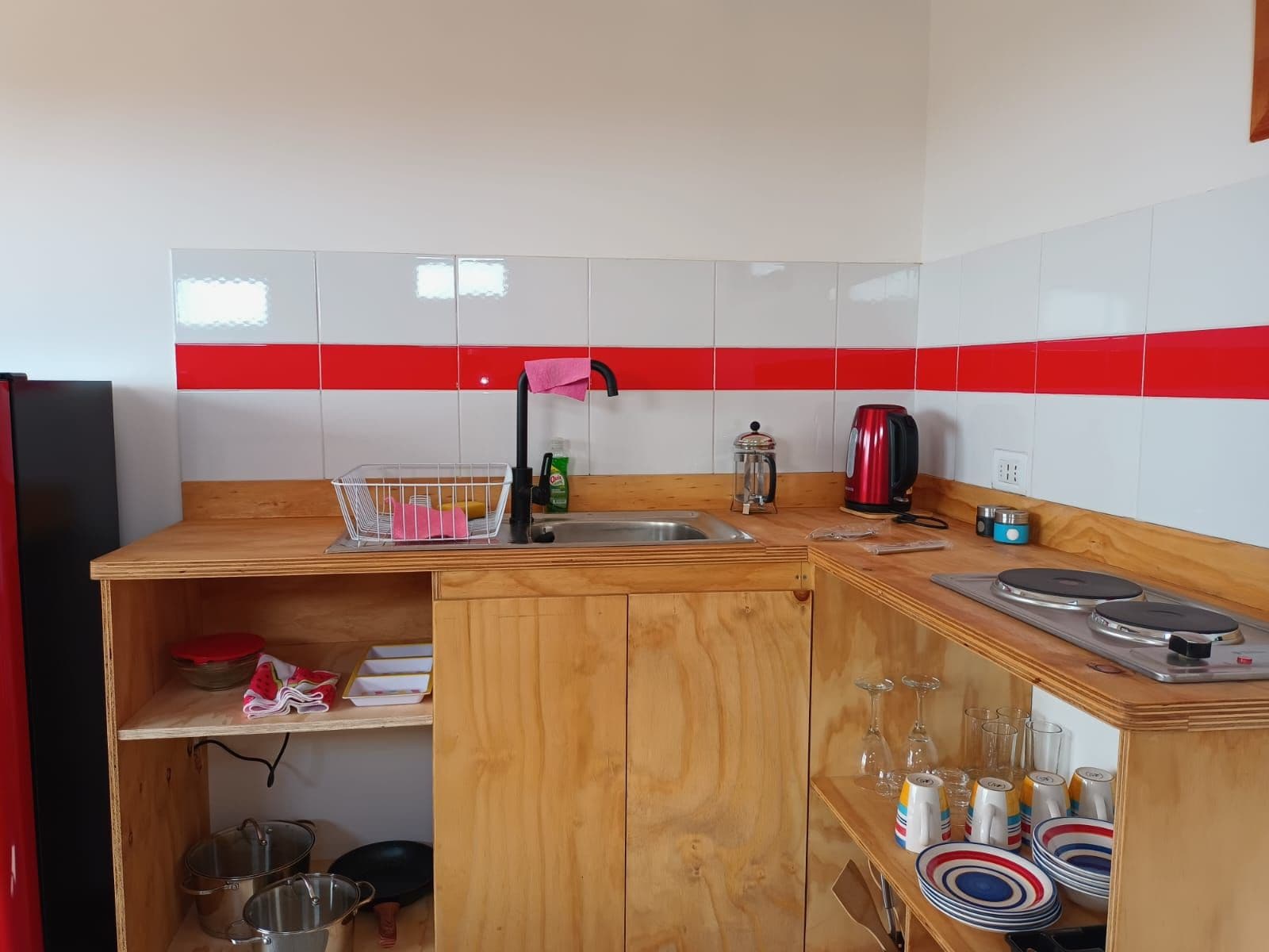Una cocina compacta equipada con un lavamanos, hervidor y diferentes utensilios.