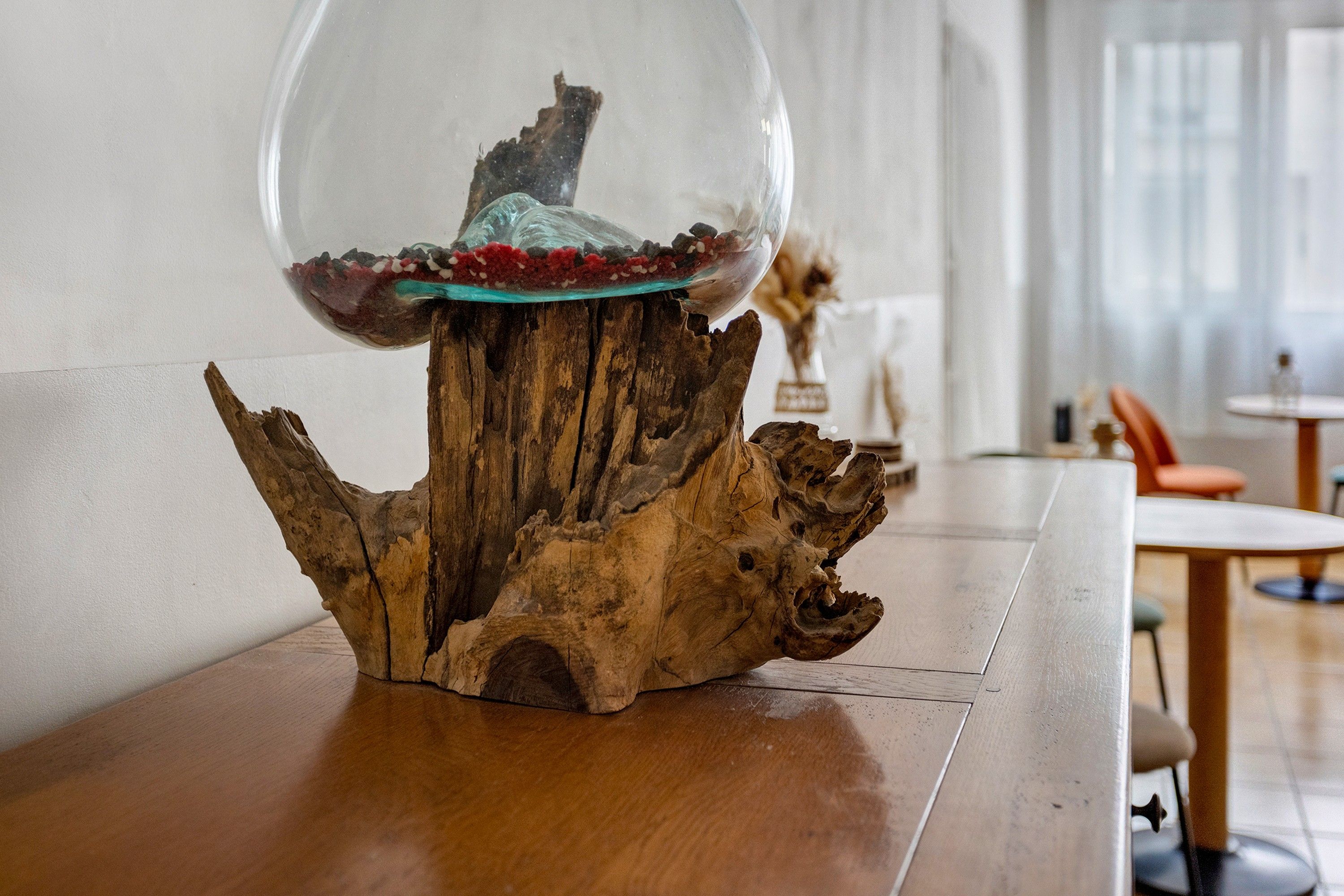 A wooden table with a glass-top centerpiece featuring a decorative arrangement.