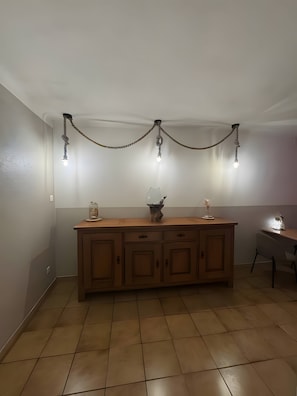 Una cocina con un armario de madera, una mesa de comedor y luces colgantes.