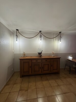 Una cocina con un armario de madera, una mesa de comedor y una lámpara colgante.
