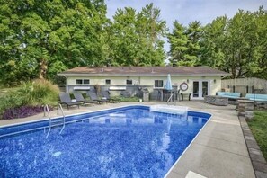Ein Schwimmbecken mit Liegestühlen und einem Haus im Hintergrund.