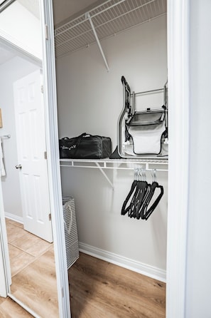 A walk-in closet with a white door, a hanging rack with utensils, and a suitcase on the shelf. - Bluegrass Cove - Private HOT TUB- Sleeps 6 (Owensboro)