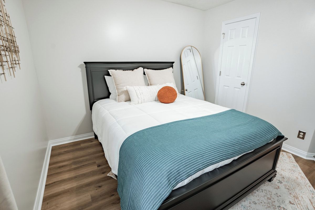 A bedroom with a bed, a white door, and a wooden floor.