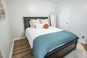 A bedroom with a bed, a white door, and a wooden floor. - Bluegrass Cove - Private HOT TUB- Sleeps 6 (Owensboro)