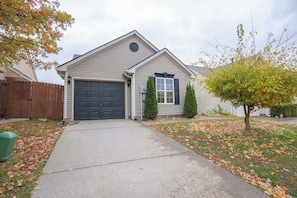 A single-story house with a garage, a front yard with a tree, and a wooden fence. - Bluegrass Cove - Private HOT TUB- Sleeps 6 (Owensboro)