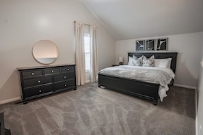 Une chambre à coucher avec un lit, une commode et un miroir rond accroché au mur.