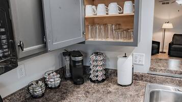 Een keuken met granieten aanrecht, koffiezetapparaat, waterkoker en een inbouw wijnrek.