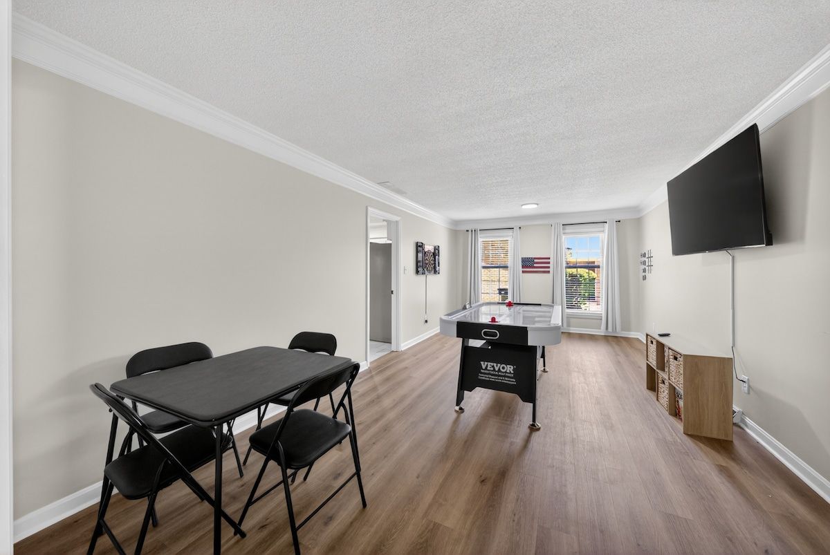 Quarto com mesa de bilhar, televisão na parede e vista para o exterior através de uma porta.