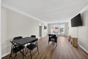 A room with a pool table, a television mounted on the wall, and a view of the outdoors through a door. - Bluegrass Springdale | Air Hockey & Darts (Owensboro)