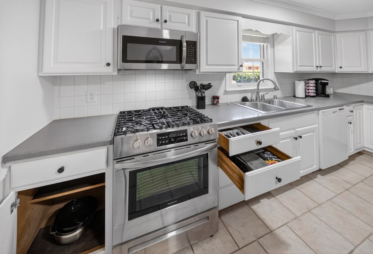 A modern kitchen with white cabinets, stainless steel appliances, and a built-in oven.