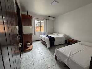 A hotel room with a bed, a desk, a wardrobe, a window, and a ceiling light.