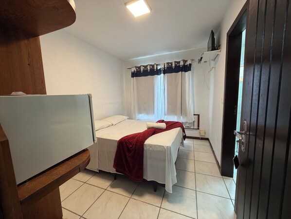 A room with a bed, a desk, and a door.