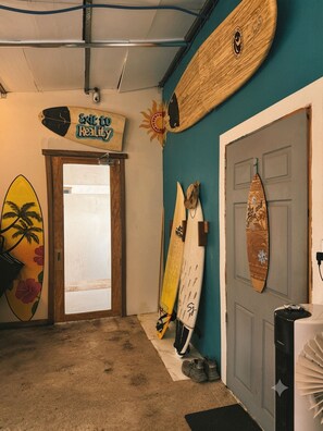 A room with surfboards against the wall, a door with a sign, and a ceiling fan. - Modern Dome Stay Near the Beach with Mountain Views (San Alfonso)