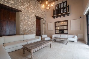 Un salón espacioso con paredes de piedra, una mesa de centro de madera y sofás blancos.