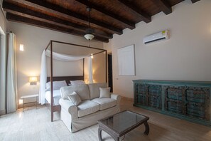 A bedroom with a four-poster bed, a sofa, and a glass coffee table. - Luxury 7 Bedroom Villa in Walled City (Cartagena de Indias)